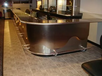 A curved stainless steel bar front with a polished foot rail