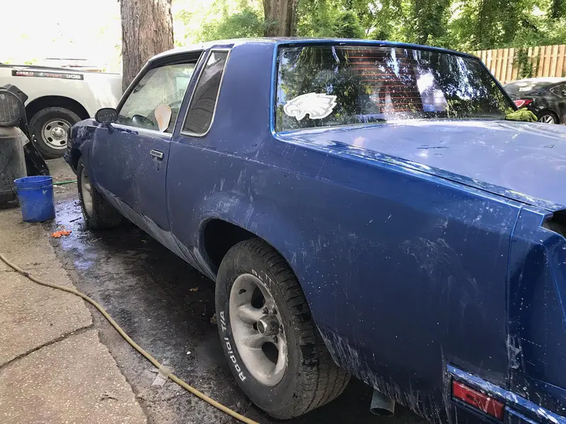 A blue Oldsmobile mid body work, filler and primer on the quarter panel