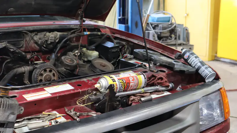 A red pickup with its hood up and the engine opened for repair