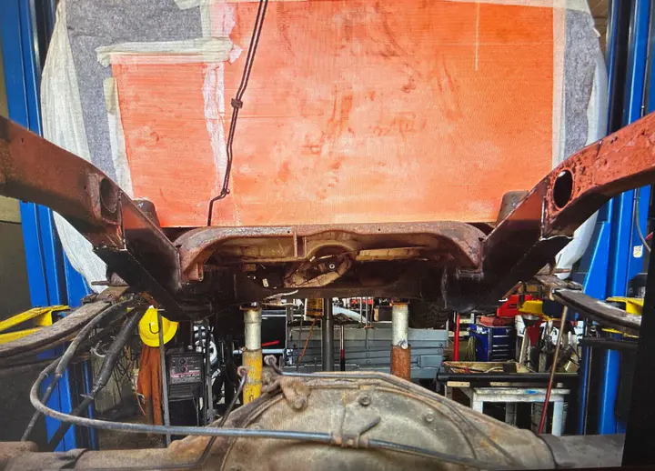 Looking up at the rear frame from under the truck, rust cleaned back to the rails