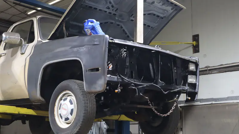 A two-tone GMC pickup up on the lift with the hood open