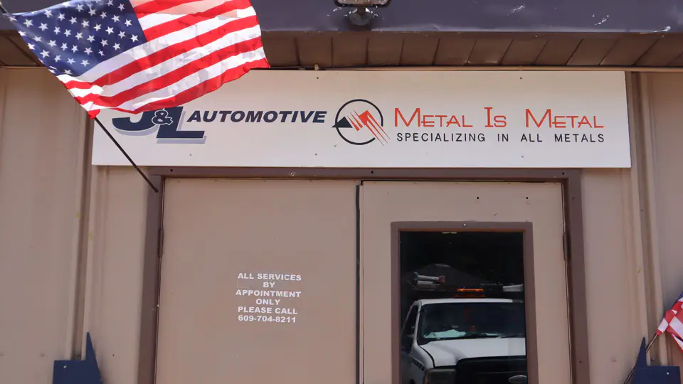 The J&L Automotive and Metal Is Metal sign over the shop door, an American flag flying beside it