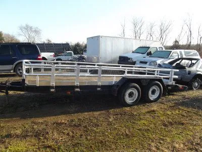 A long aluminum-railed trailer parked in the yard