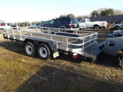 A tandem-axle trailer with aluminum rails, parked in the yard